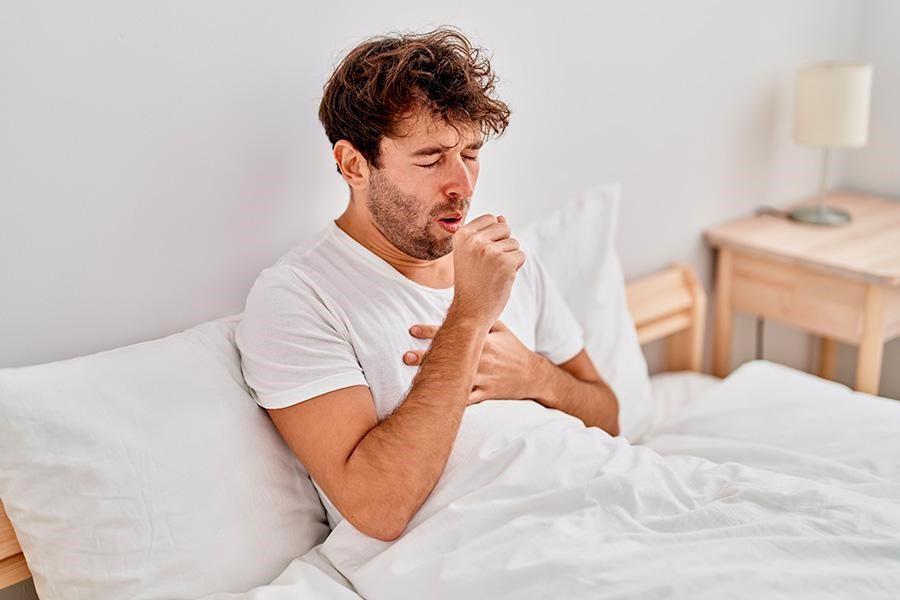 Muž kašle v posteli